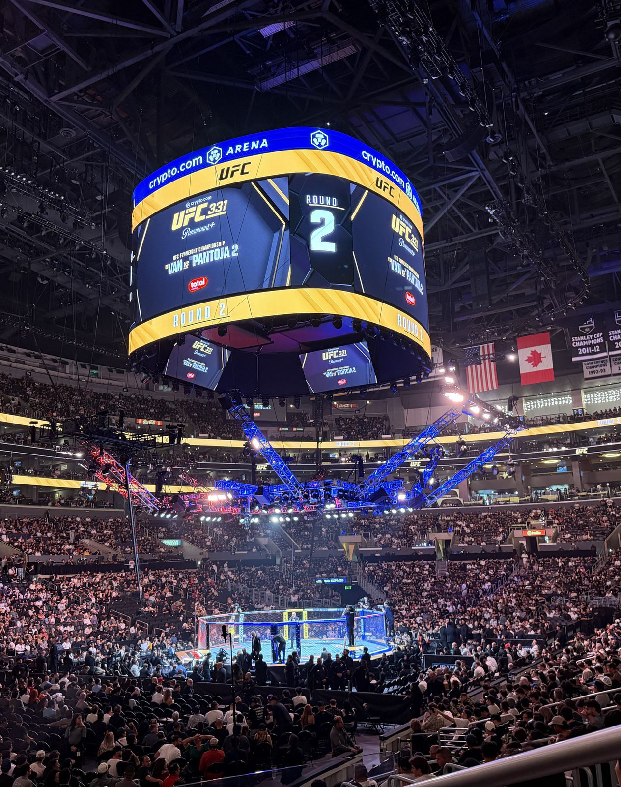 Inside Crypto.com Arena on fight night, the scoreboard above the Octagon showing UFC and round two