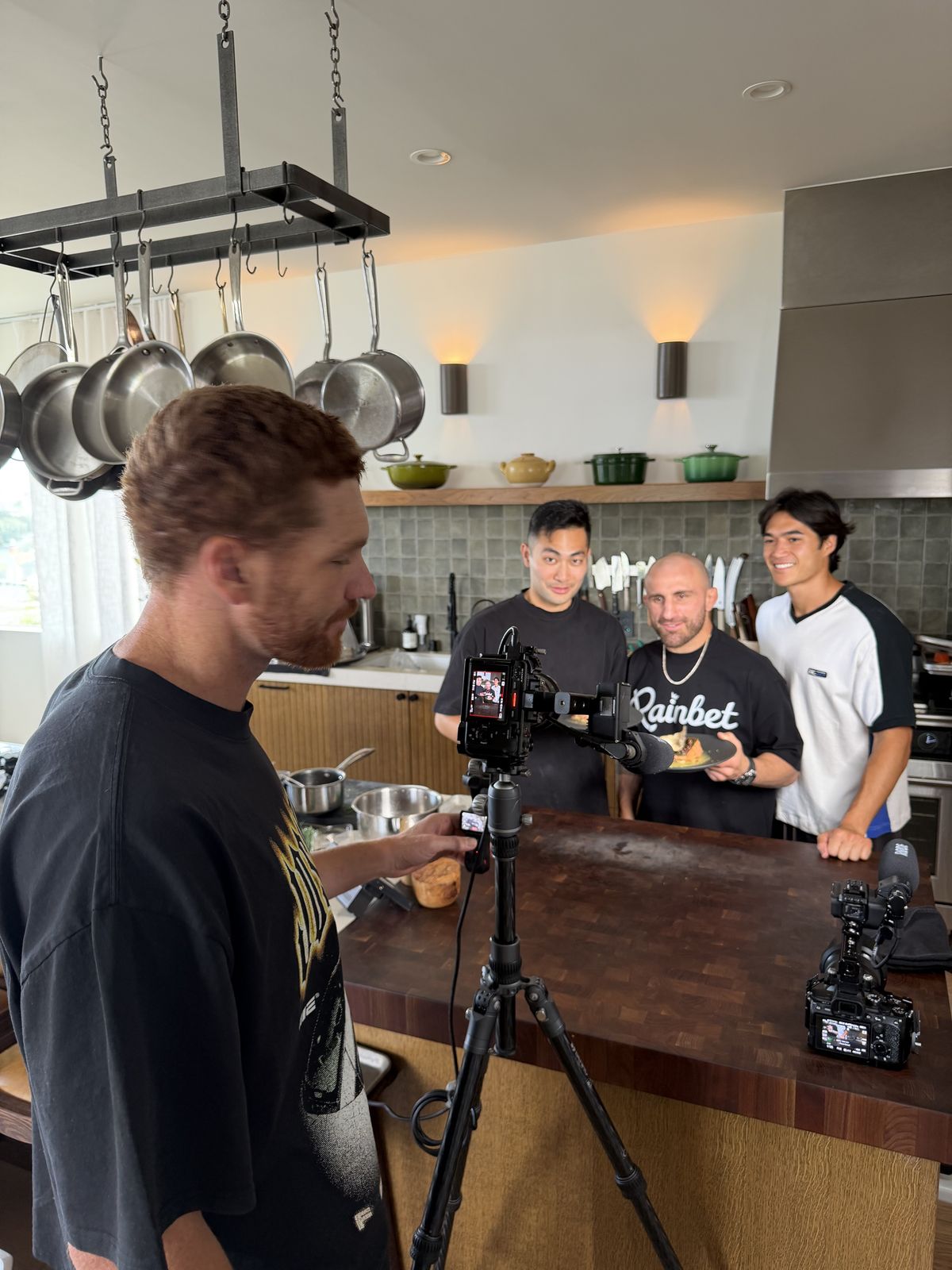 A camera operator filming a cooking segment in a home kitchen