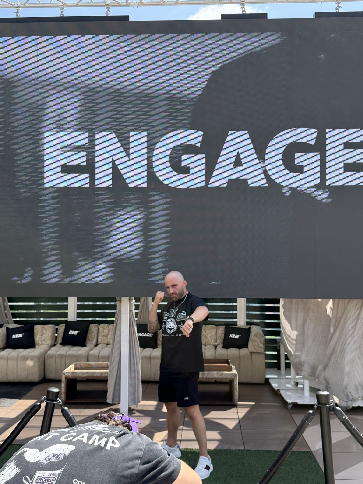 A large ENGAGE screen above the pop-up set, with a man standing beneath it