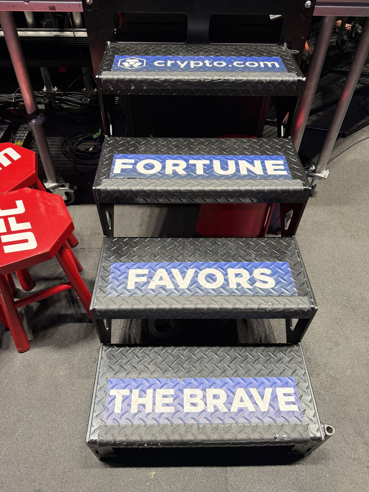Backstage steps printed with the words Fortune Favors The Brave beside red UFC stools