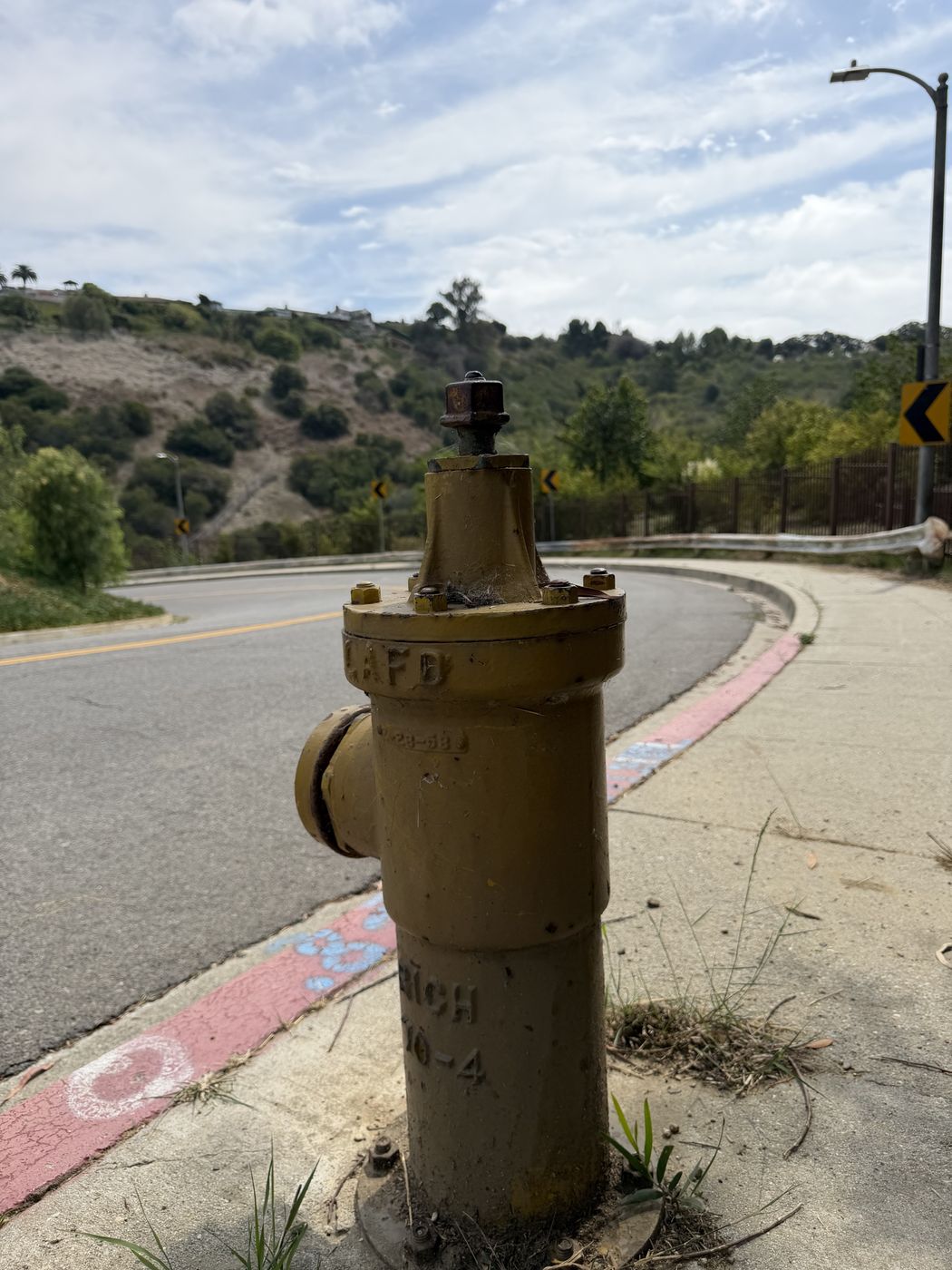 An old yellow fire hydrant on a curving hillside road