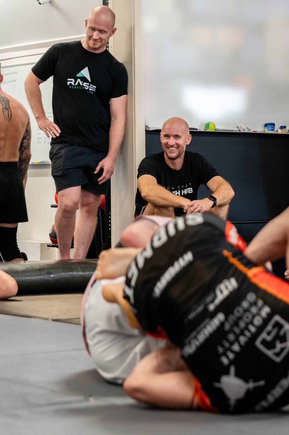 Chris Jaffrey of Raise Performance, in his Raise tee, with Mick Baines watching mat work during UFC 325 camp.