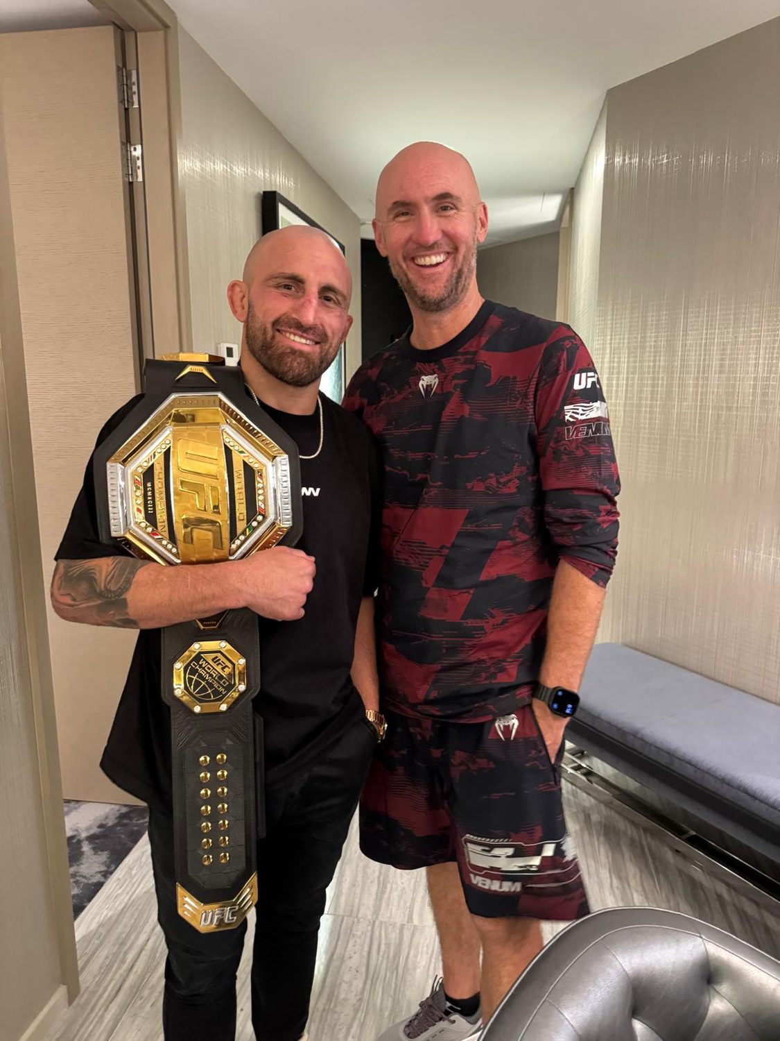 Alexander Volkanovski with the UFC featherweight title belt alongside Mick Baines after the UFC 325 win.