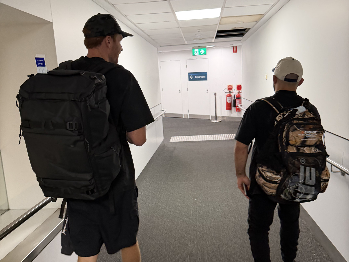 Two men walking a terminal corridor with backpacks on