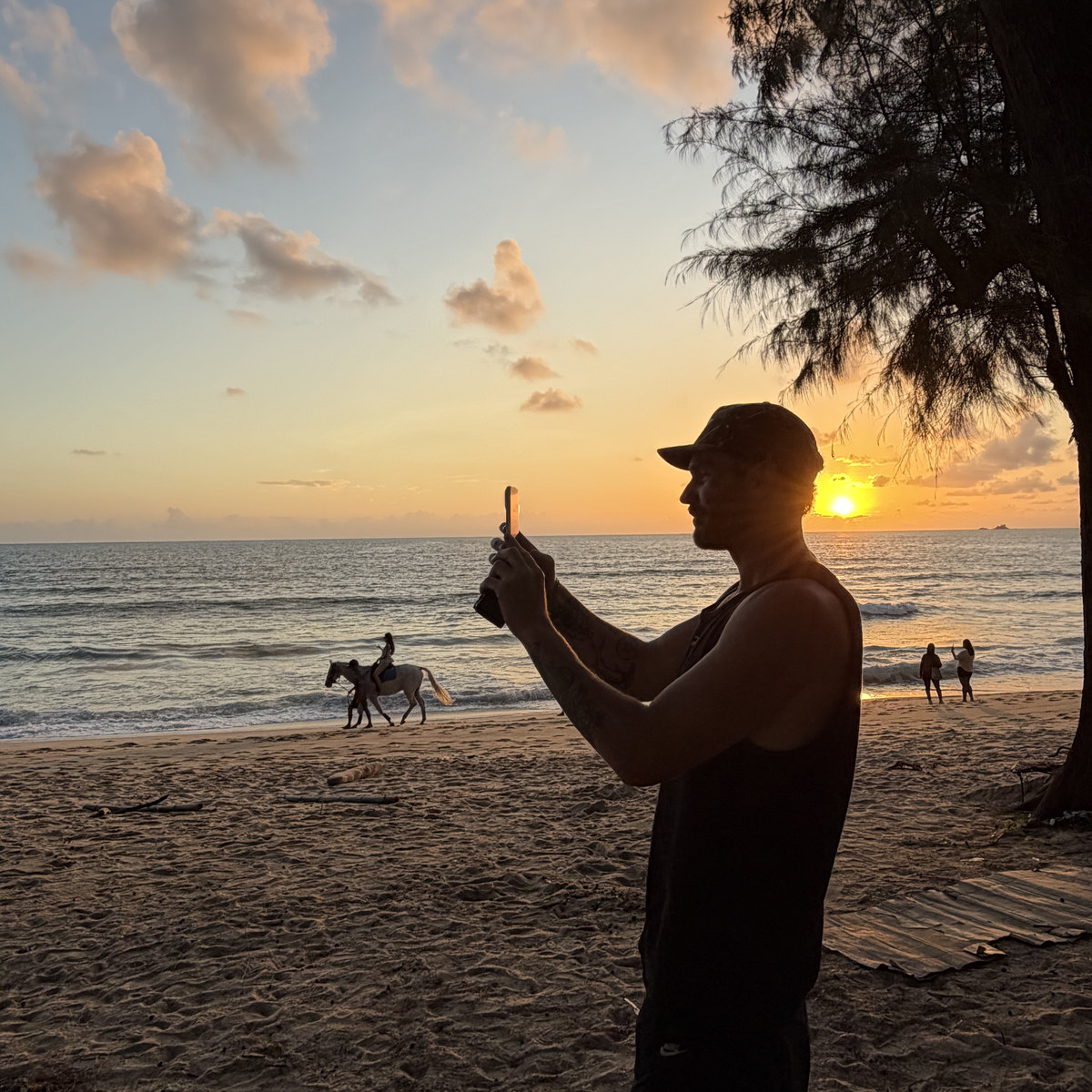 A man filming the sunset as a horse and rider pass